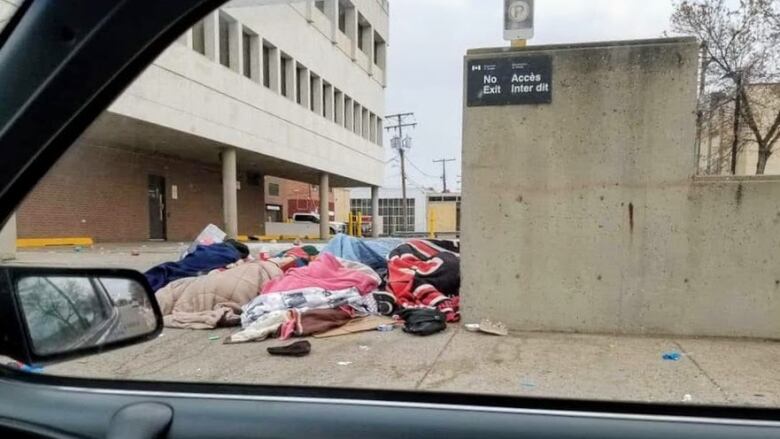 People in blankets lay outdoors near a sidewalk