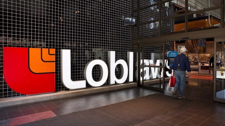 A man carrying a shopping bag walks past a huge sign bearing the words 