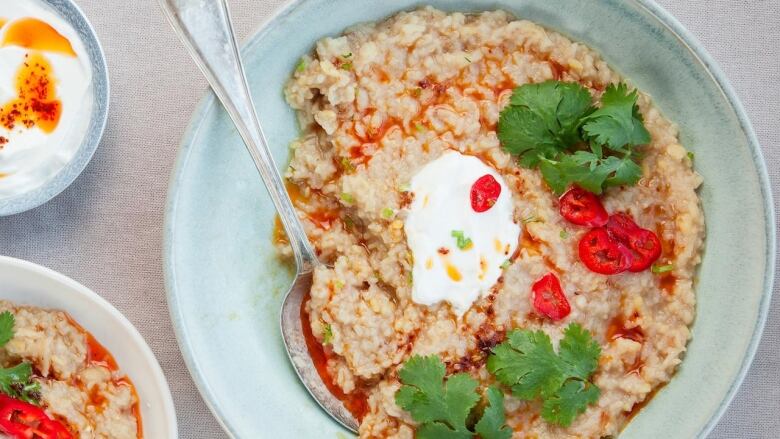 Overhead shot of a bowl of Khichdi topped with red chili slices, cilantro and a dollop of yogurt. 