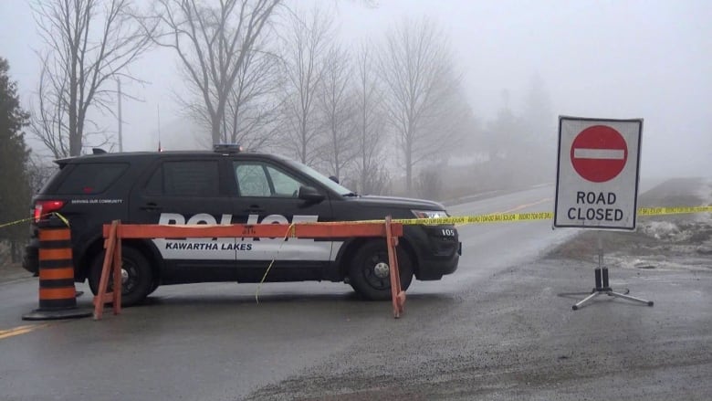 A police cruiser parked in front of caution tape.