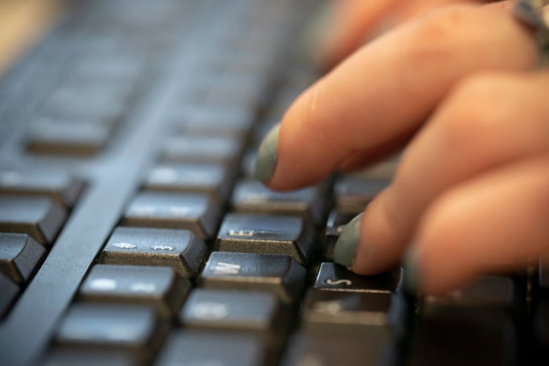 Painted fingernails are seen typing on a keyboard.