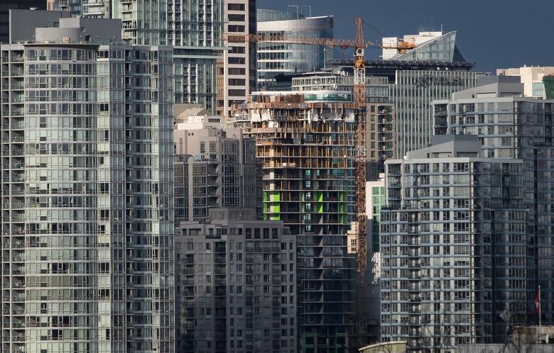 A city skyline with apartment towers including at least one with a crane that is under construction