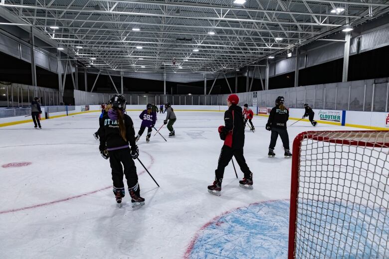 Ringette players in an outdoor rink with a roof.