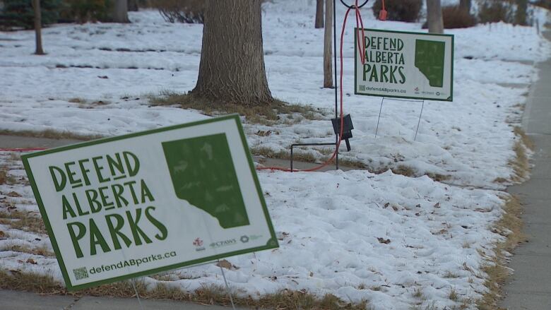 'Defend Alberta Parks' signs stand on neighbouring, partially snow-covered lawns in Calgary.