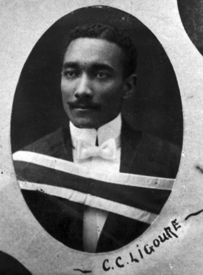 A old photo of a Black man in a suit and bowtie and a moustache