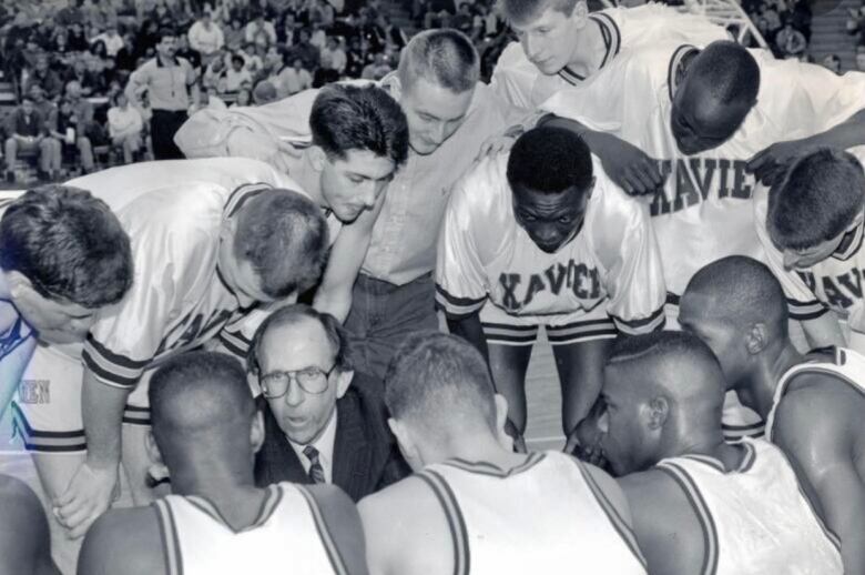 A basketball coach kneels down in the middle of a huddle as he gives instruction to his players, in this file photo.