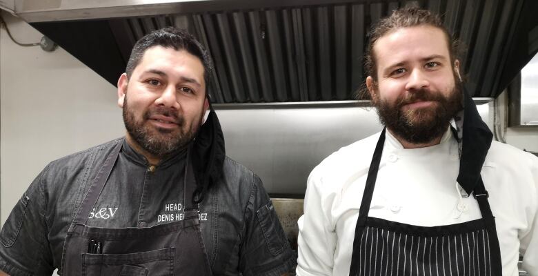 Two men in chef coats in commercial kitchen