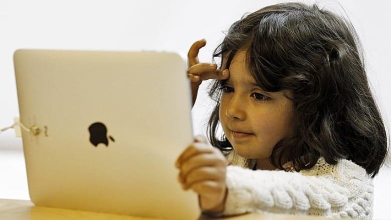 A small child watches a tablet.