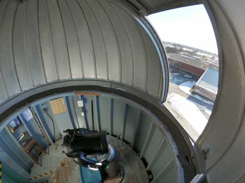 A telescope inside an observatory dome overlooking a university campus