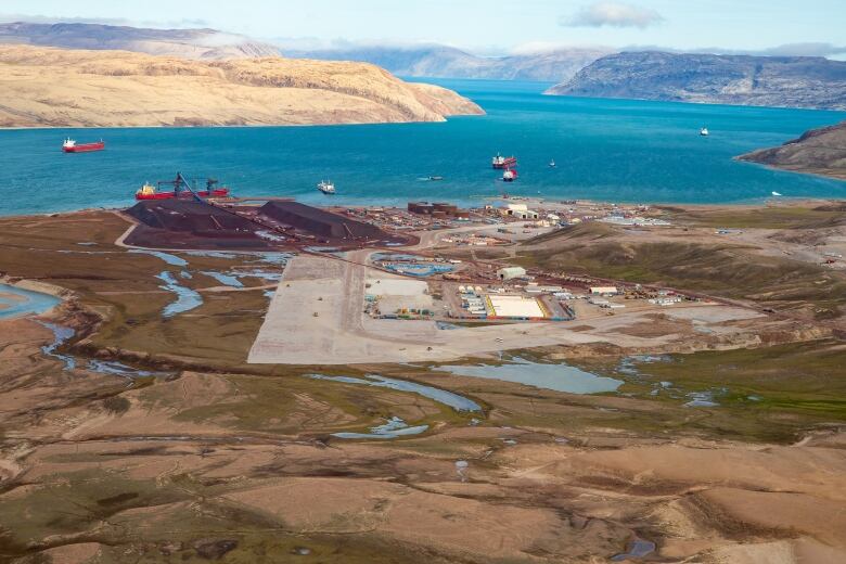 Ships in water in background, land with operations in foreground.