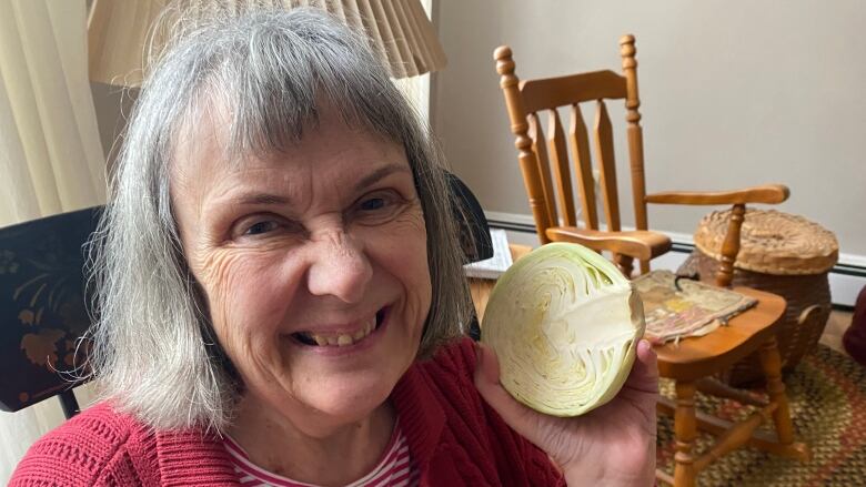 A woman holds a cabbage.