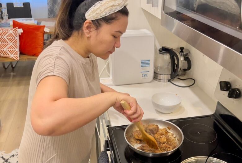 J.B. Anilao cooks Filipino adobo for her family in her northeast home. She says cooking is helping with homesickness.