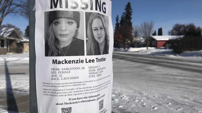 A poster taped to a light post shows two images of a young woman. It's text includes the word 