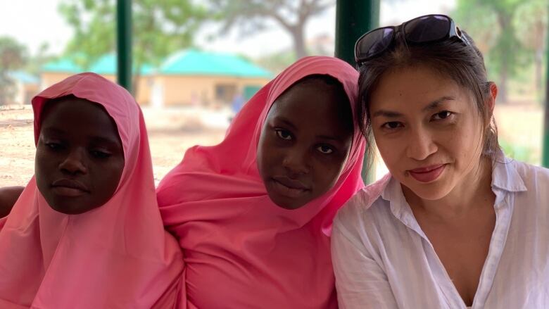 Three women look at the camera as their picture is taken.