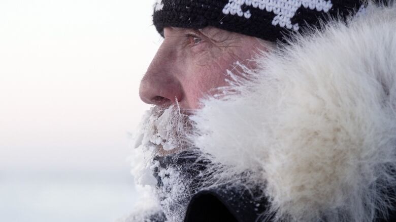 Dennis Compayre, beard crusted with ice, looks into distance.