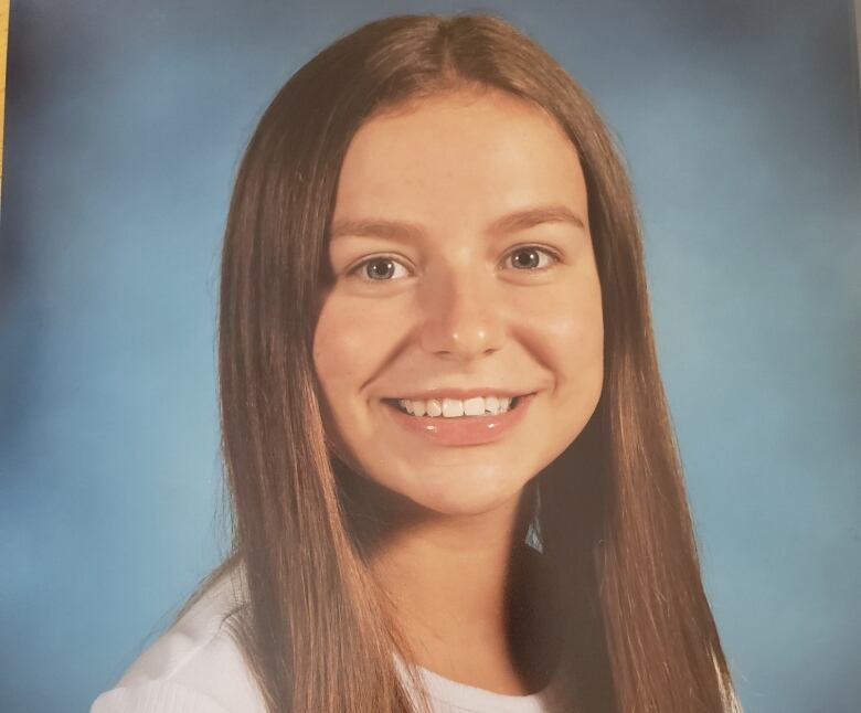 A teenager girl smiles in a school portrait. 