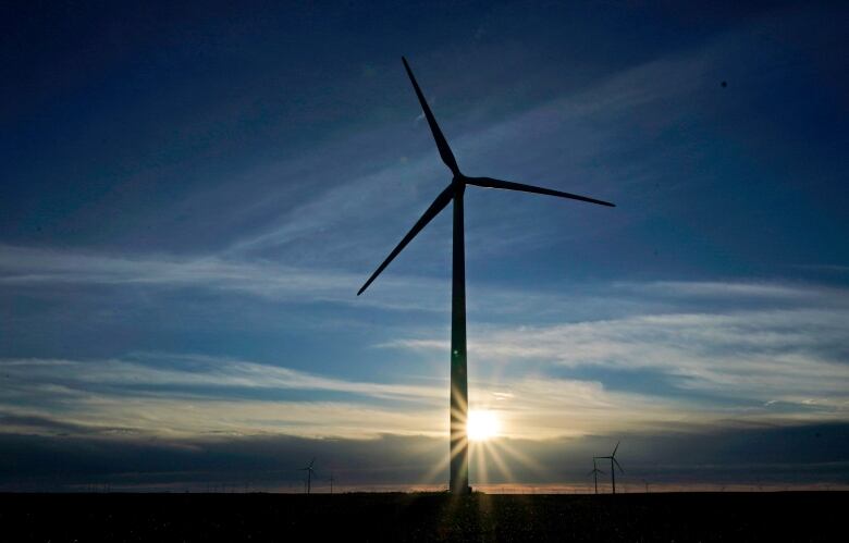 A windmill is seen against a background of the setting sun.