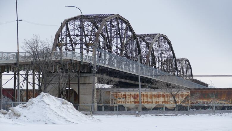 A steel bridge over rail cars in the winter.