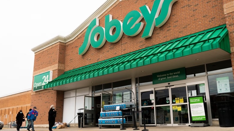 Four people are seen entering a grocery store.