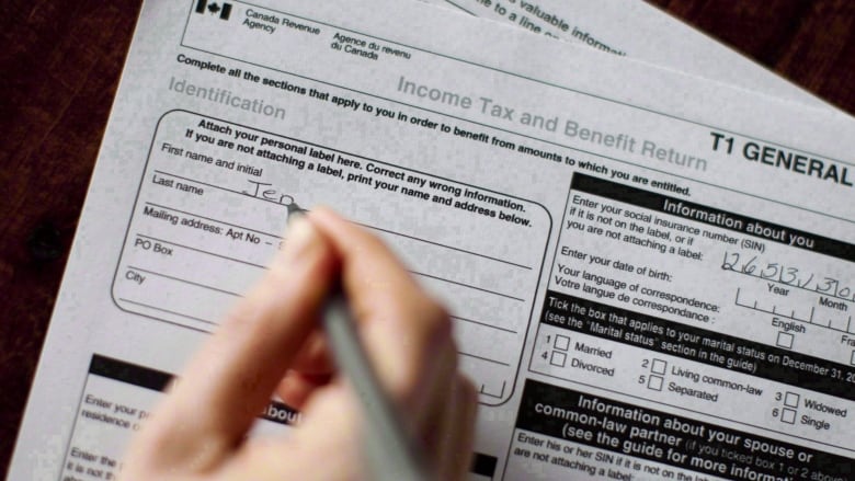 A person fills out an income tax return with a pen.