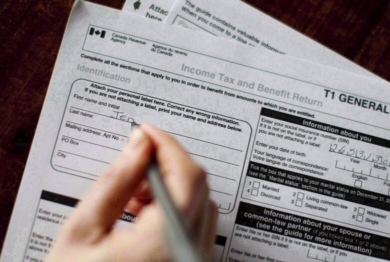 A person fills out an income tax return with a pen.