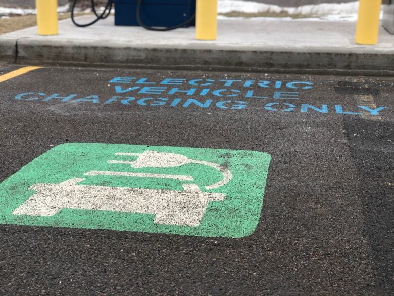 A stencil painted-space for an electric vehicle is show against the backdrop of a charger.