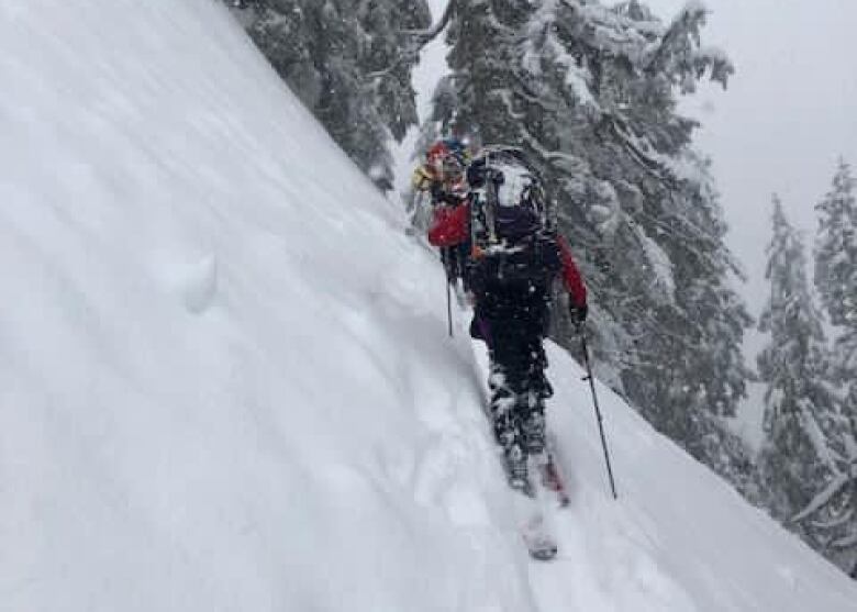 A skier skis across a steep mountain