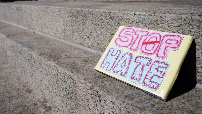 A sign on stairs that says Stop Hate