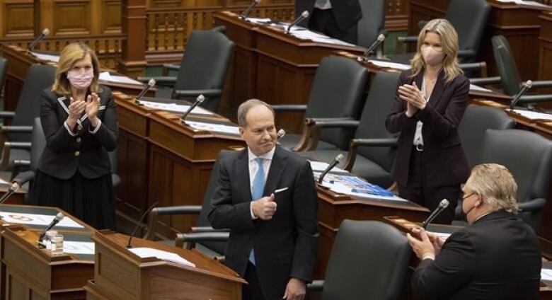 Finance Minister Peter Bethlenfalvy gets a standing ovation from a few masked cabinet colleagues