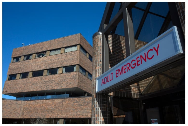 A hospital sign reading Adult Emergency, above the entrance to a hospital.