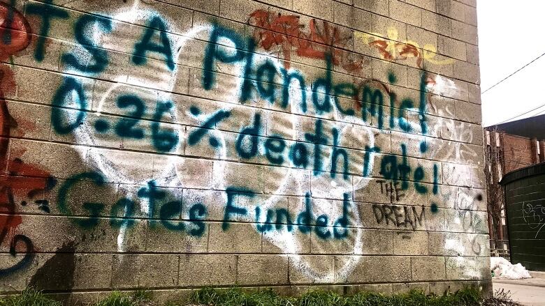 Graffiti on a wall alludes to conspiracy theories about COVID-19 deaths.