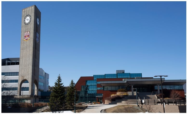 A university building stands next to a large clock tower.