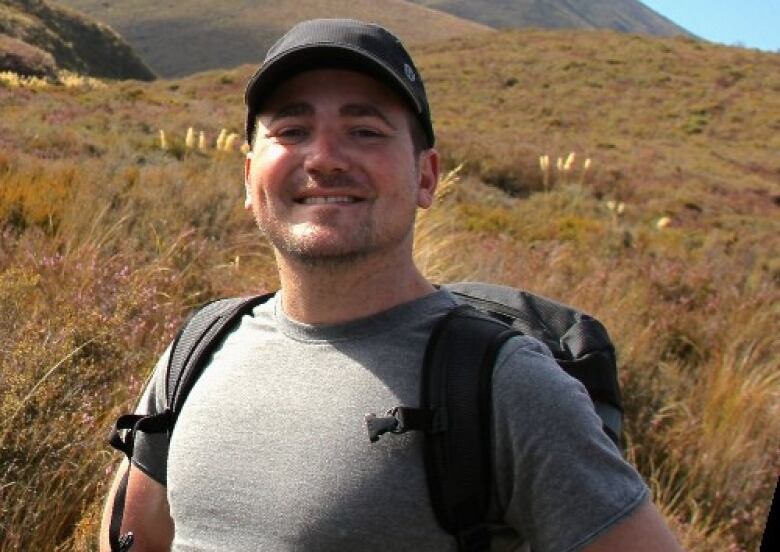 A man standing in a field, smiling.