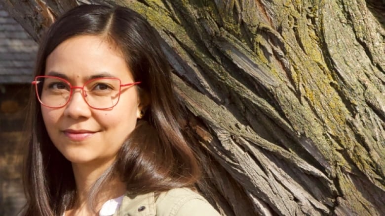 female author with red glasses and brown hair.