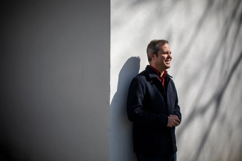 A man leans against a wall outdoors.