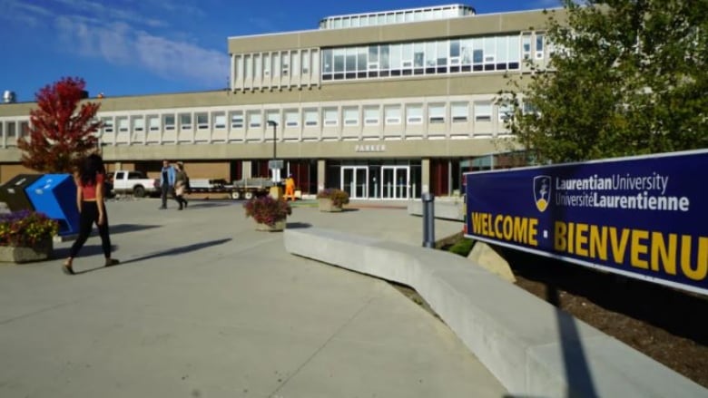 A university campus with a blue sign that says Weclome.