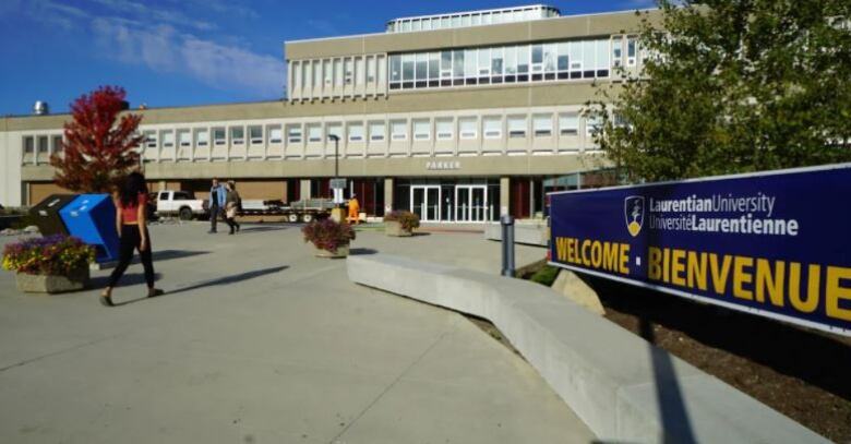 A university campus with a blue sign that says Weclome.