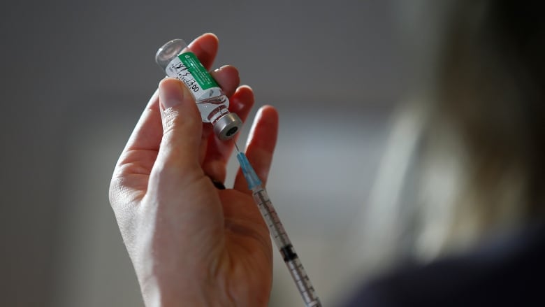 Hand holds a vaccine and needle.