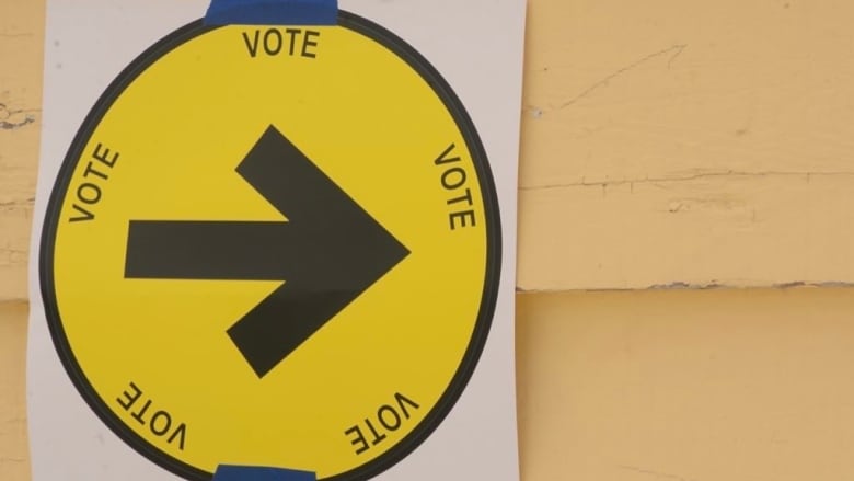 A yellow sign with an arrow and the word 'vote.'