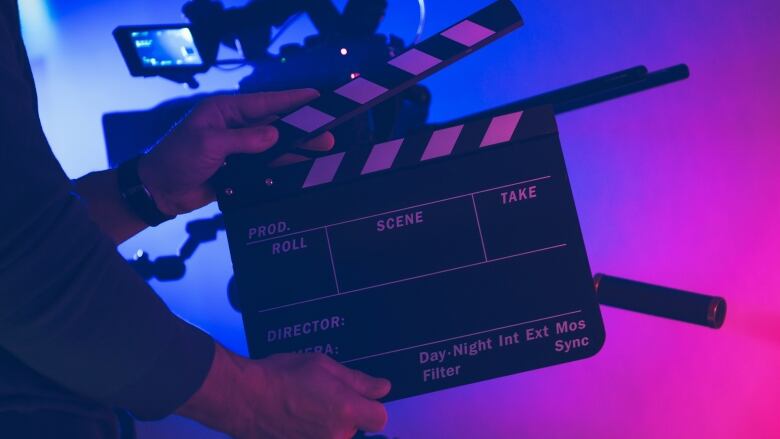 Two hands hold up a clapperboard