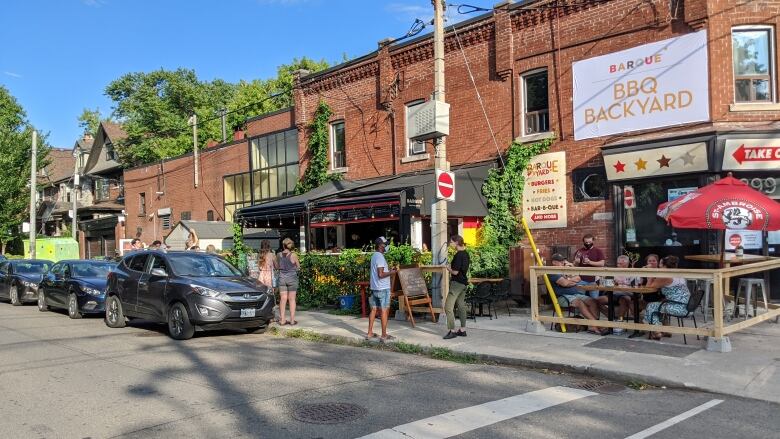 Brick building with a small fenced patio running beside a street.