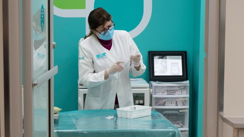 A pharmacist in a lab coat in a blue-painted room.