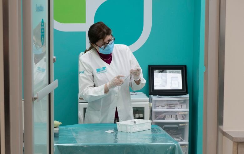 A pharmacist in a lab coat in a blue-painted room.