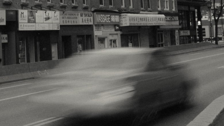 a blurry car drives down a street in Calgary's Chinatown