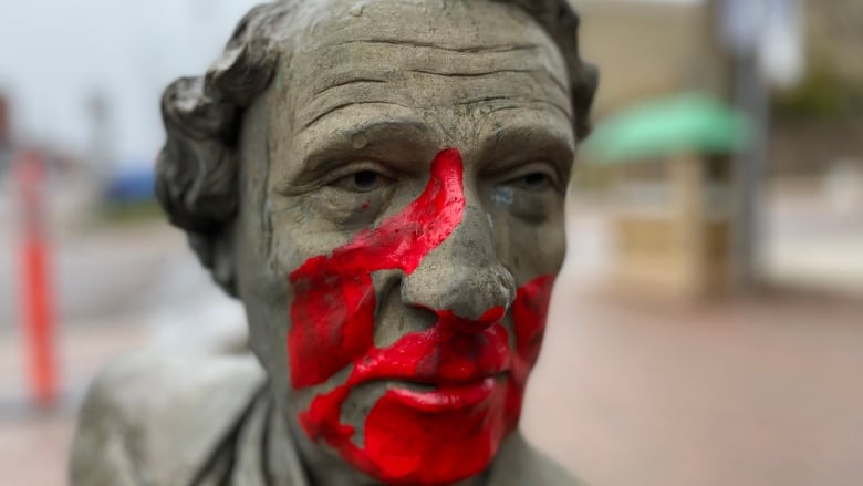 A red hand print marks the face of the bronze John A Macdonald.