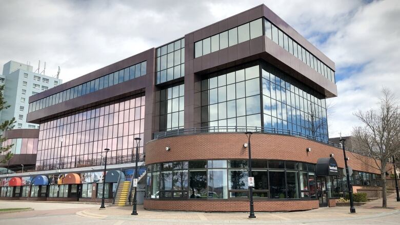 A tall building with lots of windows and a curved red brick front is shown.