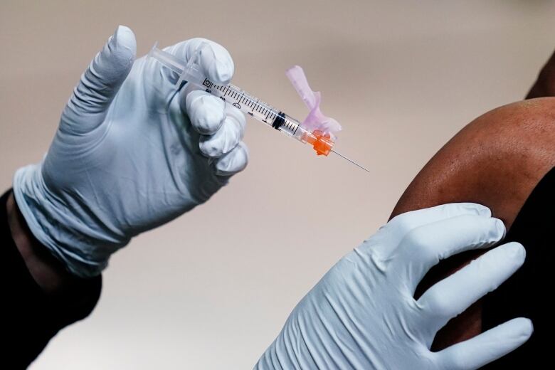 A member of the Philadelphia Fire Department administers a COVID-19 vaccine to a person at a vaccination site setup at a Salvation Army location in Philadelphia on March 26, 2021.