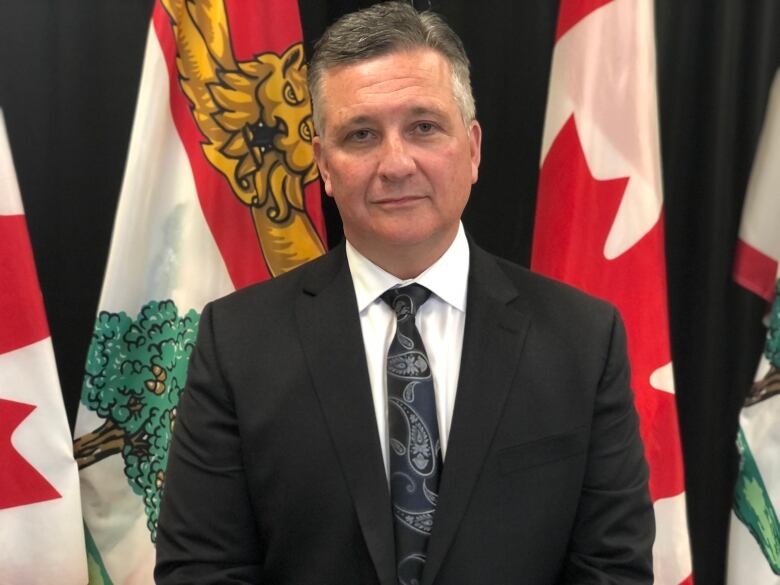 Malpeque MP Heath MacDonald standing in from of Canada and P.E.I. flags.