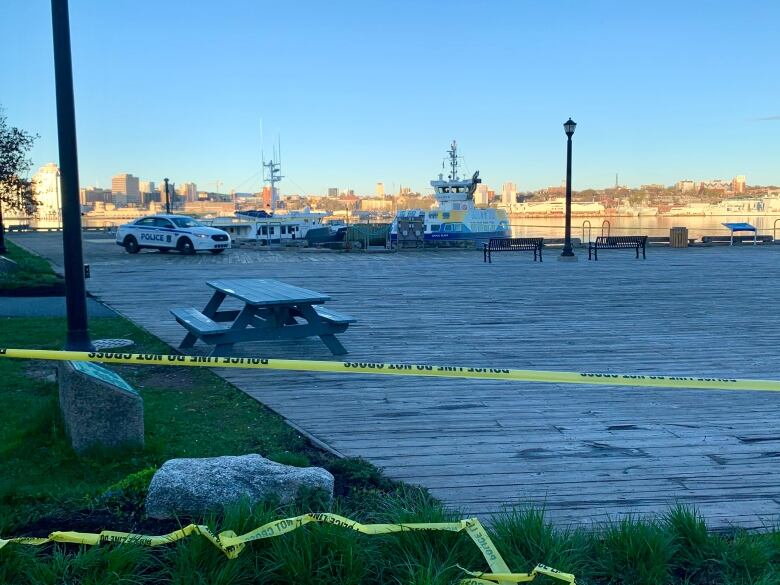 Yellow caution tape is seen blocking off a waterfront boardwalk.