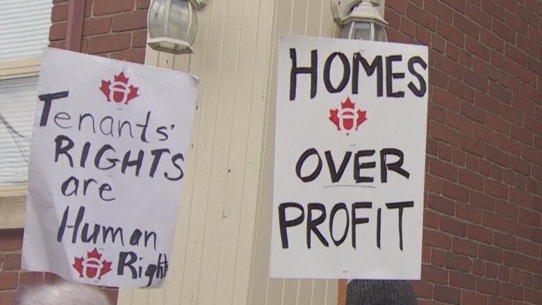 Tenants at a protest hold signs saying 